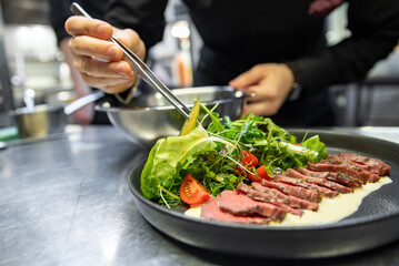 Poster - chef hand preparing Roastbeef salad with vegetables on restaurant kitchen