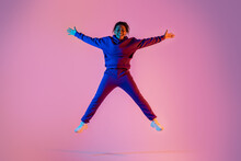Full Body Length Of Sporty African American Young Woman Jumping Up In Star Shape, Having Fun Over Pink Neon Background