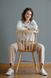 © DragonImages - Smiling mature woman sitting on chair and looking looking at camera