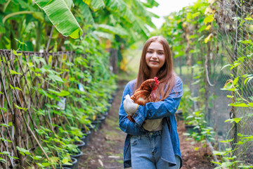 Wall Mural - young girl farmer holding a hen in the garden