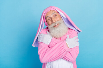 Wall Mural - Photo of optimistic positive pensioner dressed pink bunny costume hug himself satisfied in comfort isolated on blue color background