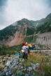 © Sergey - A couple of tourists, a man and a woman, are happy in each other's arms, standing at the destination. On the top of the mountain. Vertical photo. The route to the Chalaadi glaicer. Georgia