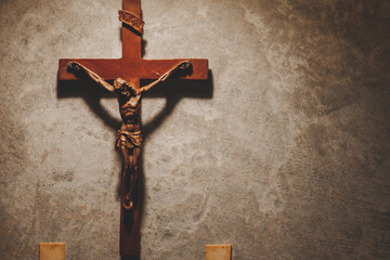 The Crucifix of Jesus Christ hanged on gray concrete wall background with copy space for your text, christian background