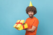 Sad upset man in party cone holding present box, opened gift, feeling sorrow.