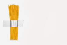 Long Raw Spaghetti Is Taped To A White Wall With Gray Duct Tape. Free Space For Text. Contemporary Food Related Art. Italian National Dish In The Form Of Spaghetti