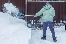 Man Cleans Snow With Shovel At Gate Of Country House. Snow Removal In Snowy Winter. High Quality Photo