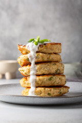 Wall Mural - Greek zucchini fritters Kolokithokeftedes on gray background. Zucchini pancakes with feta and herbs, served with greek yogurt.