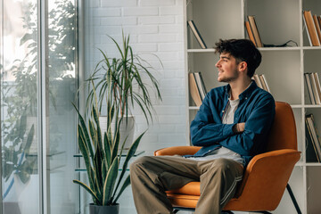 portrait of young man at home sitting on the sofa looking out the window