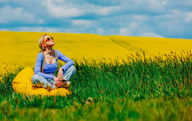 Sticker - Beautiful female in rainbow LGBT suspenders for pants sitting in bean chair in rapeseed field