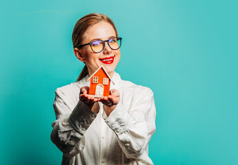 Sticker - Portrait of beautiful blonde in white shirt with little house on blue background