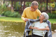 © NanSan - Elderly couple husband and wife happy asian people giving love and care Wheelchair in the park relaxing in spring, relaxing and walking outside at the park.