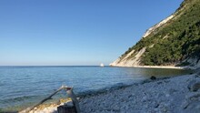 Beautiful Scenery At The Sailing Beach (Spiaggia Della Vela) On The Adriatic Sea In Portonovo With A Vision Of Monte Conero (Mount Conero) Touched By The Minutely Rippling Waters Reaching Some Rocks