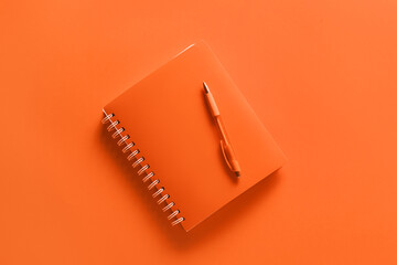 notebook with pen on orange background