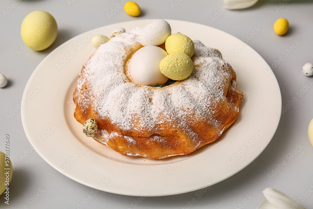 Plate with sweet Easter cake and eggs on light background