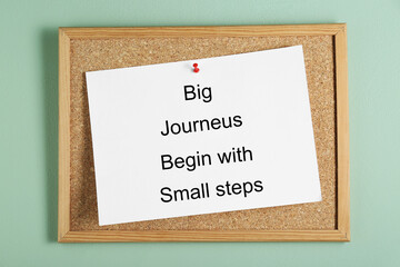 Wall Mural - Corkboard and phrase Big Journeys Begin With Small Steps on light green background, top view. Motivational quote