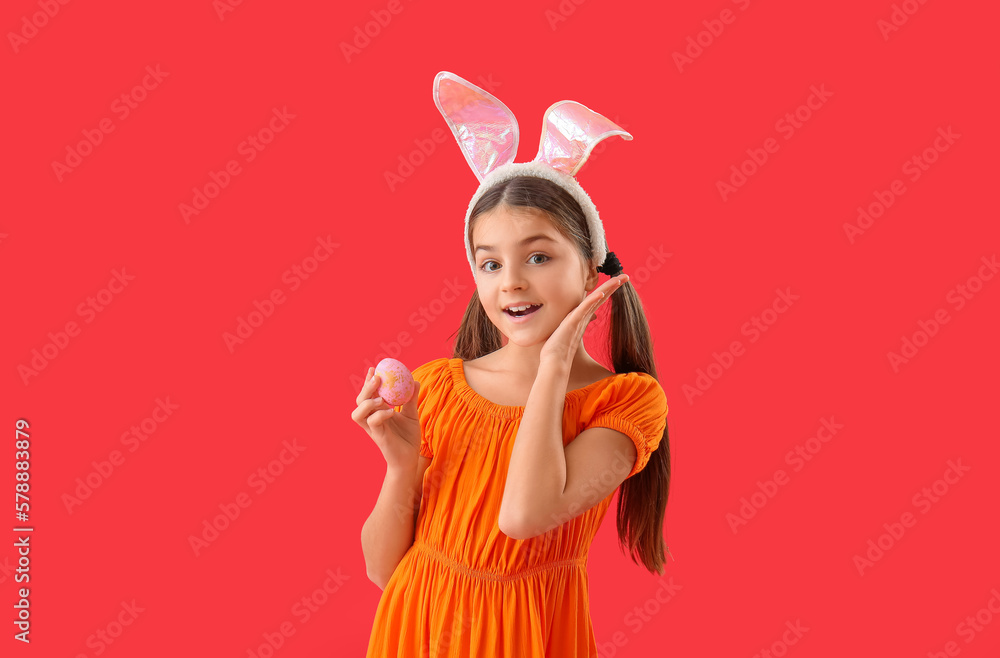 Little girl in bunny ears with Easter egg on red background