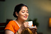 Relaxed woman enjoying drinking tea or coffee at home during morning at home - concept of calmness, serene and wellbeing