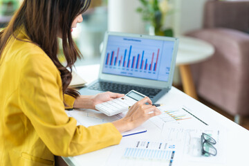 Portrait of asian business woman paying bills online with laptop in office. Beautiful girl with computer and checkbook, happy paying bills. Startup business financial calculate account concept