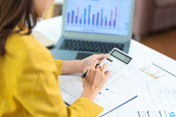 Portrait of asian business woman paying bills online with laptop in office. Beautiful girl with computer and checkbook, happy paying bills. Startup business financial calculate account concept