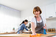 © Kawee - Caucasian senior elderly woman cleaning kitchen in house with daughter.
