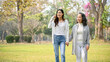 Lovely Asian female grandchild holds hands with her grandmother while strolling in the park