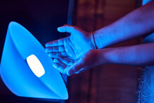 Close Up View Of Hands Illuminated By A Blue Light Bulb Led Light