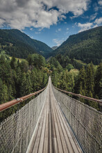 A Wooden Suspension Bridge Ending In A Forest In The Mountains
