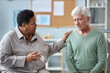 © Seventyfour - Portrait of black senior woman comforting depressed white haired man sharing stories in mental health support group