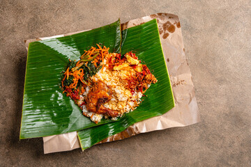 Wall Mural - Indonesian padang food or nasi bungkus with padang fried chicken (indonesian : Ayam goreng padang)