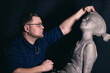© primipil - Man sculptor creates sculpt bust clay human woman sculpture. Statue craft creation workshop.