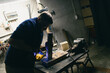 © primipil - Man carpenter drilling wood with a drill at workshop