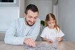 © Julija - man playing puzzle with daughter at home. Focus on man