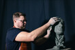 © primipil - Man sculptor creates sculpt bust clay human woman sculpture. Statue craft creation workshop.