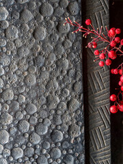 Black, rough forged iron surface with space for text or logo, and a bunch of bright red peppercorn fruits.