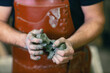 © primipil - Man sculptor dressed leather apron with clay in hands. Statue craft creation workshop.