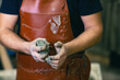 © primipil - Man sculptor dressed leather apron with clay in hands. Statue craft creation workshop.