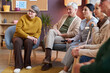 Full length view at group of elderly people watching TV in retirement home together
