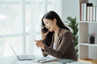 © Kritdanai - Asian businesswoman in formal suit in office happy and cheerful during using smartphone and working