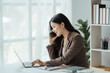 © Kritdanai - Asian businesswoman in formal suit in office happy and cheerful during using smartphone and working