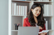 © Kritdanai - Asian businesswoman in formal suit in office happy and cheerful during using smartphone and working