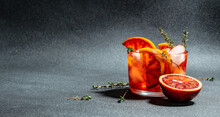 Refreshing Alcoholic Cocktail With Sicilian Red Oranges, Aperitif On A Dark Background. Long Banner Format. Top View