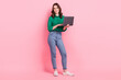 © deagreez - Full size photo of positive gorgeous intelligent girl wear jeans green shirt holds laptop writing message isolated on pink background