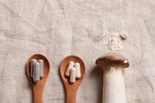 Mushroom And Natural Herbal Pills On Wood Spoons On Textile Background. Environmental Friendly , Healthy, Medical Supplement Concept. Copy Space.
