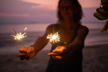 Sticker - woman holding sparkles celebrating on tropical beach