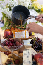 Toffee Being Poured Over Cheese On Platter Filled With Cheese And Fruit