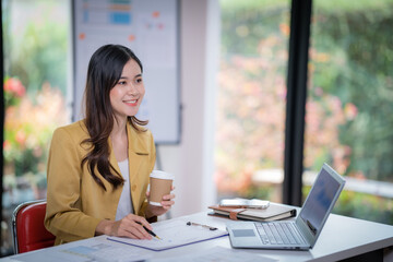 Happy businesswoman holding a cup of coffee and Smile while analyzing weekly schedule in the office.