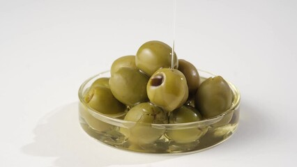 Wall Mural - Close-up of olives placed in a transparent tray, on white background. Olive oil sprinkled on top. Olive oil is good for health and beauty