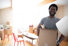 Portrait Of Smiling Young Man Carrying Cardboard Box, Moving Out Of Home