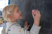 Preschool Girl Student Drawing On Blackboard In Classroom