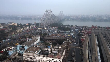 Wall Mural - Aerial view of architectural landmark Howrah Bridge and Howrah Railway Station on a smoggy day in Kolkata, West Bengal, India. Kolkata is one of the world's most polluted cities.